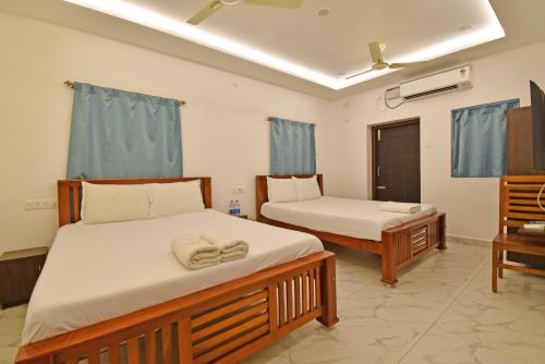 two beds in a room with blue curtains at Hotel De Lux Splendid in Pondicherry