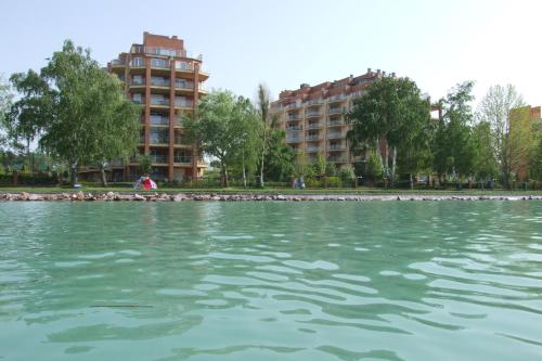 a large body of water with buildings in the background at Galerius Golden Beach Apartment in Siófok