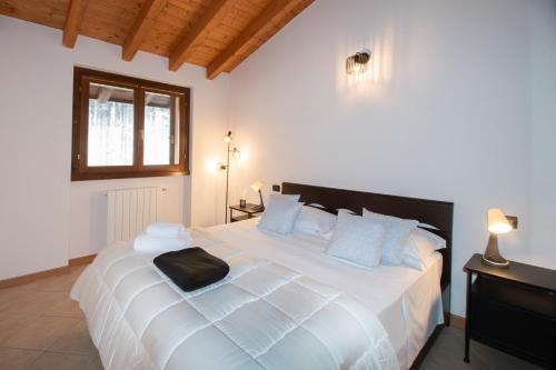 a bedroom with a large white bed with blue pillows at Panorama & Pisicna Lago Endine in Ranzanico