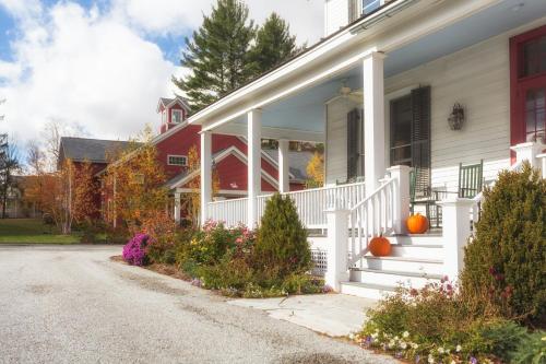 a white house with pumpkins on the porch at The Inn at Manchester in Manchester