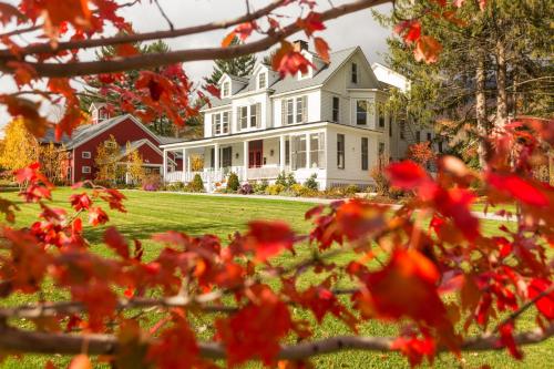 a large white house with red flowers in the foreground at The Inn at Manchester in Manchester