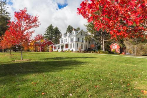 a large white house with a tree with red leaves at The Inn at Manchester in Manchester