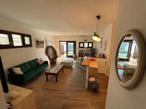 a living room with a green couch and a mirror at Sardinia house with beautiful view near sea in Brunella