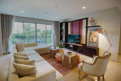 a living room with white furniture and a large window at Luxury Apartment at AYANA Residences in Jimbaran