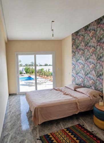 a bedroom with a large bed with a large window at Blue Escape in Oulad Teïma
