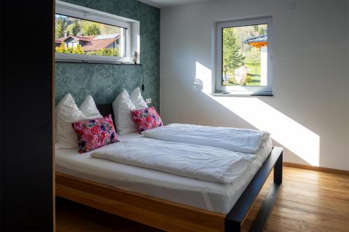 a bed in a room with two windows at Bayerwald-Bungalow in Grattersdorf