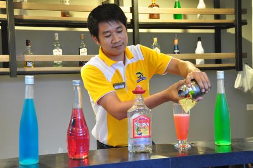 
a man pouring a glass of orange juice into a glass at Flipper House Hotel - SHA Extra Plus in Pattaya
