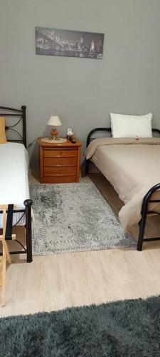 a bedroom with two beds and a wooden night stand at Panos House - Warm and cozy retreat in Tríkala