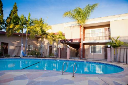 a swimming pool in front of a building with palm trees at Budget Inn Anaheim near Disneyland Drive in Anaheim