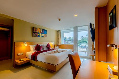 a bedroom with a bed and a desk and a television at Aspery Hotel - SHA Certified in Patong Beach