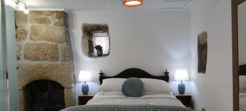 a bedroom with a bed and a stone fireplace at Casinha Das Portas in Castelo Bom