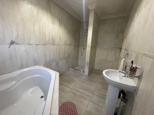 a bathroom with a bath tub and a sink at Alamaison in Umtali
