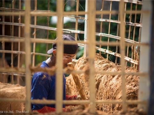 a baseball player holding a bat in a cage at The Mud - Eco Hotel in Ban Bang Po