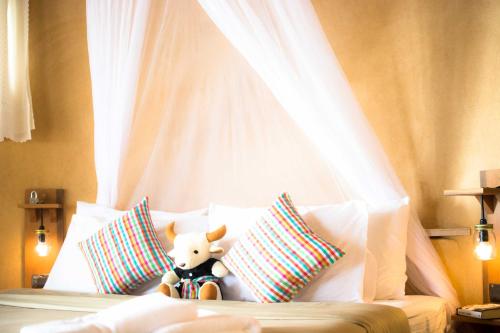 a stuffed animal sitting on a bed with pillows at The Mud - Eco Hotel in Ban Bang Po