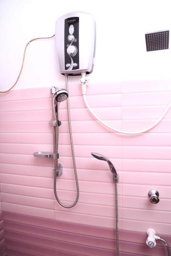 a pink bathroom with a shower and a phone on the wall at Freedom Lodge Yala in Tissamaharama