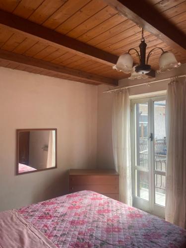 a bedroom with a bed and a mirror and a window at Casa nonna Bruna in Montebruno