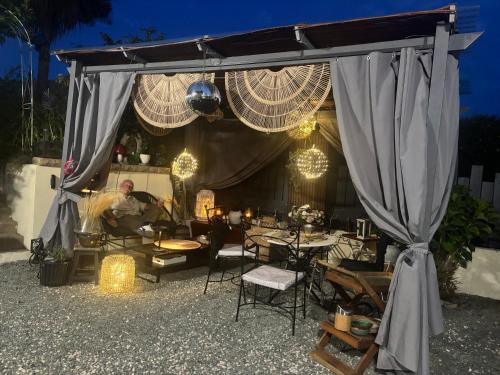 a man sitting under a tent with tables and chairs at Maison, atypique, proche, mer in Plérin