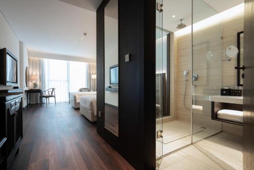 a bathroom with a glass shower and a bedroom at Khách Sạn The Grand Dragon in Móng Cái