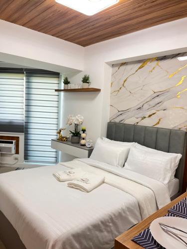 a bedroom with a large bed with a painting on the wall at Nest & Rest Suites Azure North in San Fernando