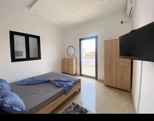 a bedroom with a bed and a flat screen tv at villa amani in Al Maqārisah