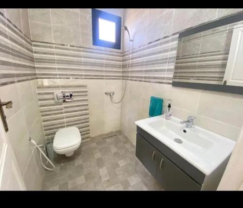 a bathroom with a white toilet and a sink at villa amani in Al Maqārisah