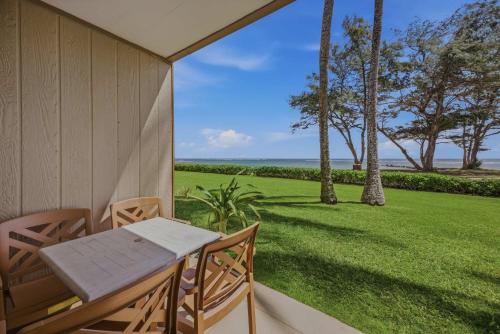 a porch with a table and chairs and a view of the ocean at Oceanfront Escape Pono Kai Resort A103 in Kapaa