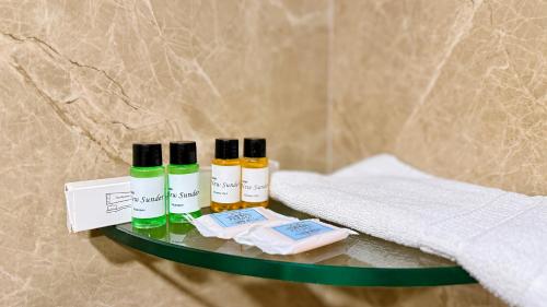 a shelf with four bottles of essential oils and a towel at Hotel New Sunder in Indore