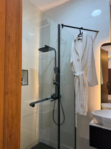 a bathroom with a shower and a white robe at M&N Apartment in Ikate