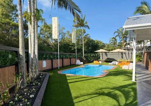 ein Garten mit Pool, Rasen und Palmen in der Unterkunft Hervey's in Hervey Bay