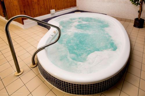 a bath tub filled with blue water in a bathroom at Wensum Valley Hotel Golf and Country Club in Norwich