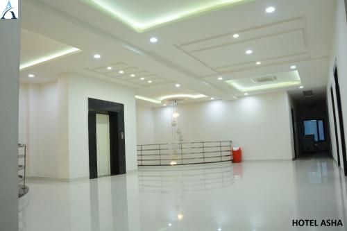 a large white room with a staircase in a building at Hotel Asha in Kannauj