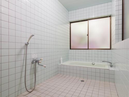 a white tiled bathroom with a shower and a tub at Yamamizuki in Shimanto