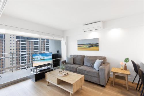 a living room with a couch and a tv at Ilikai Tower 1936 condo in Honolulu