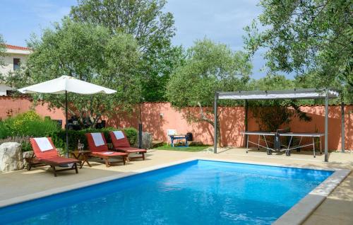 a swimming pool with chairs and a table and an umbrella at Stunning Home In Peruski in Peruški