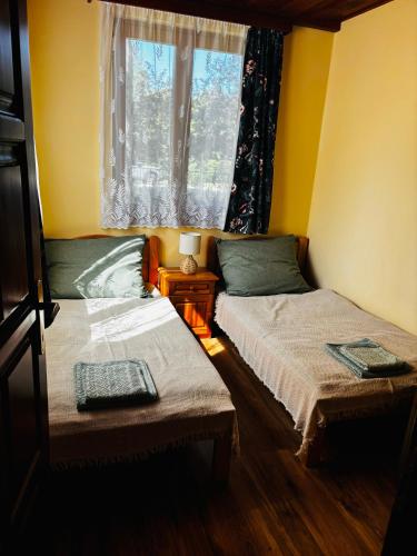two beds in a small room with a window at Viola Apartman in Zamárdi