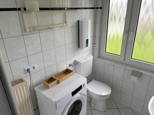 a small bathroom with a toilet and a washing machine at SielundMeer in Neuharlingersiel