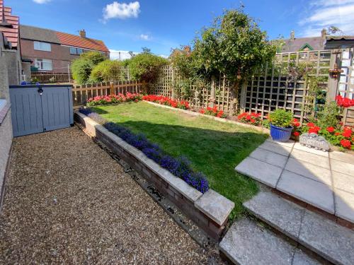a garden with purple and blue flowers and a fence at Cloverfield in Bamburgh