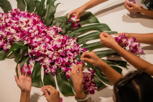 a group of people holding up pink flowers at OUTRIGGER Waikiki Paradise Hotel in Honolulu