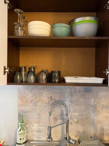 a kitchen sink with bowls and plates on a shelf at KingsWay Mezzanine in Ágios Rókkos