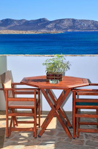 a wooden picnic table with two chairs and a potted plant at Onar Studios in Koufonisia