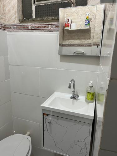 a white bathroom with a sink and a toilet at Tropical Loft in Niterói