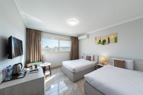a hotel room with two beds and a television at pyramids View Top in Cairo