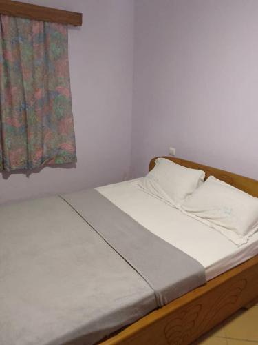 a bedroom with a bed with white sheets and a window at La casa in Kribi