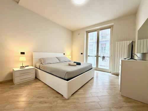 a white bedroom with a bed and a window at Dimora del Centro in Acqui Terme