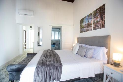 a white bedroom with a large white bed with a blanket on it at Hogar de la plata in Sanlúcar de Barrameda