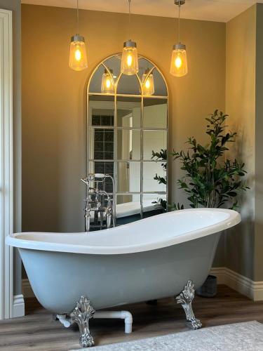 a white bath tub in a bathroom with a mirror at Kittys Haven in Castlemaine