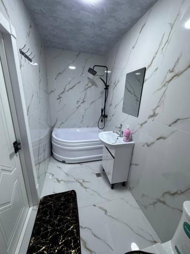 a white bathroom with a sink and a bath tub at Runa modern flat in Samarkand