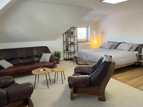a bedroom with a bed and a couch and chairs at Vila SoHo in Vysoké Mýto