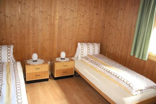 two twin beds in a room with wooden walls at Tgea sulagliva in Andeer