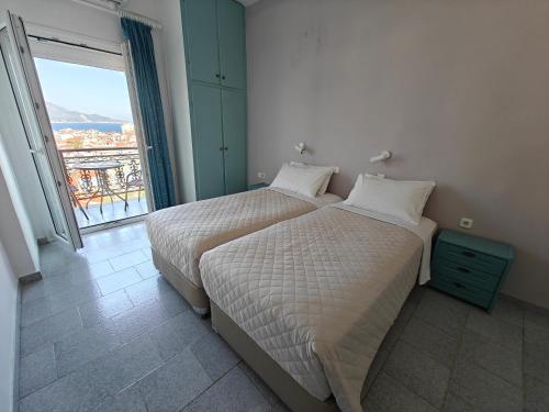 two beds in a room with a large window at Kamelia in Kokkari